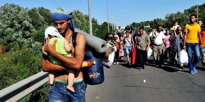 Un hombre sirio lleva a su bebé en brazos y se dirige hacia Viena, Austria. Foto: ACNUR/Mark Henley.