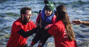 Voluntarios griegos ayudan a un niño pequeño a desembarcar al llegar a las costas de la isla griega de Lesbos, tras cruzar el mar Egeo desde Turquía. Foto: ACNUR/Achilleas Zavallis