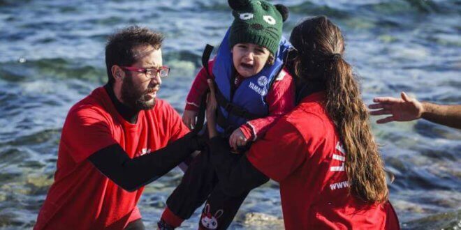 Voluntarios griegos ayudan a un niño pequeño a desembarcar al llegar a las costas de la isla griega de Lesbos, tras cruzar el mar Egeo desde Turquía. Foto: ACNUR/Achilleas Zavallis