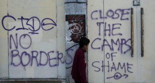 Un niño pasa delante de unas pintadas hechas en Atenas a mediados de abril durante una manifestación contra la guerra en Siria y la actitud de la UE hacia los refugiados. S. PANTZARTZI EFE