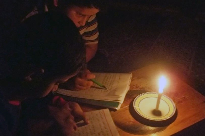 Ante la falta de electricidad, dos niños leen a la luz de una vela en Gaza. Foto: Ahmend Dallou/IRIN